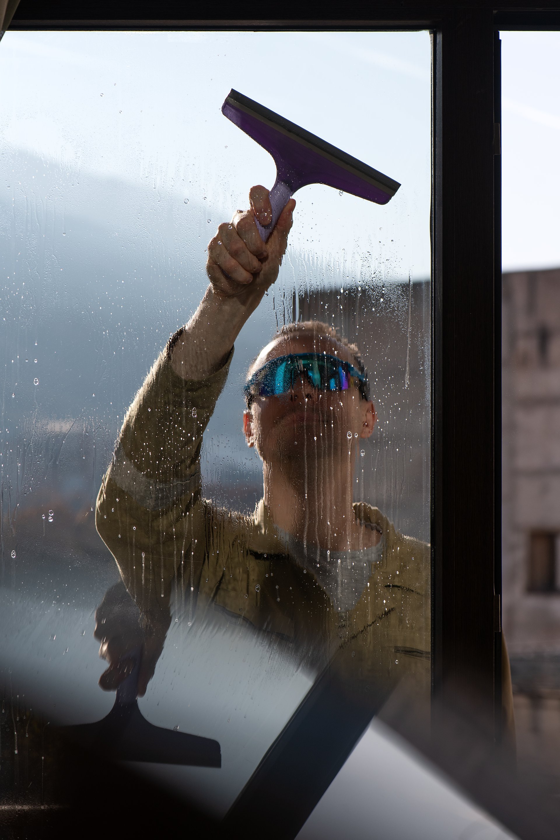 Professional window cleaning service with technician using squeegee to clean windows